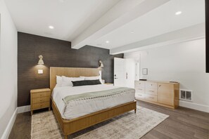 Un dormitorio moderno con una cama de madera, lámparas de noche, un armario y un espejo grande.