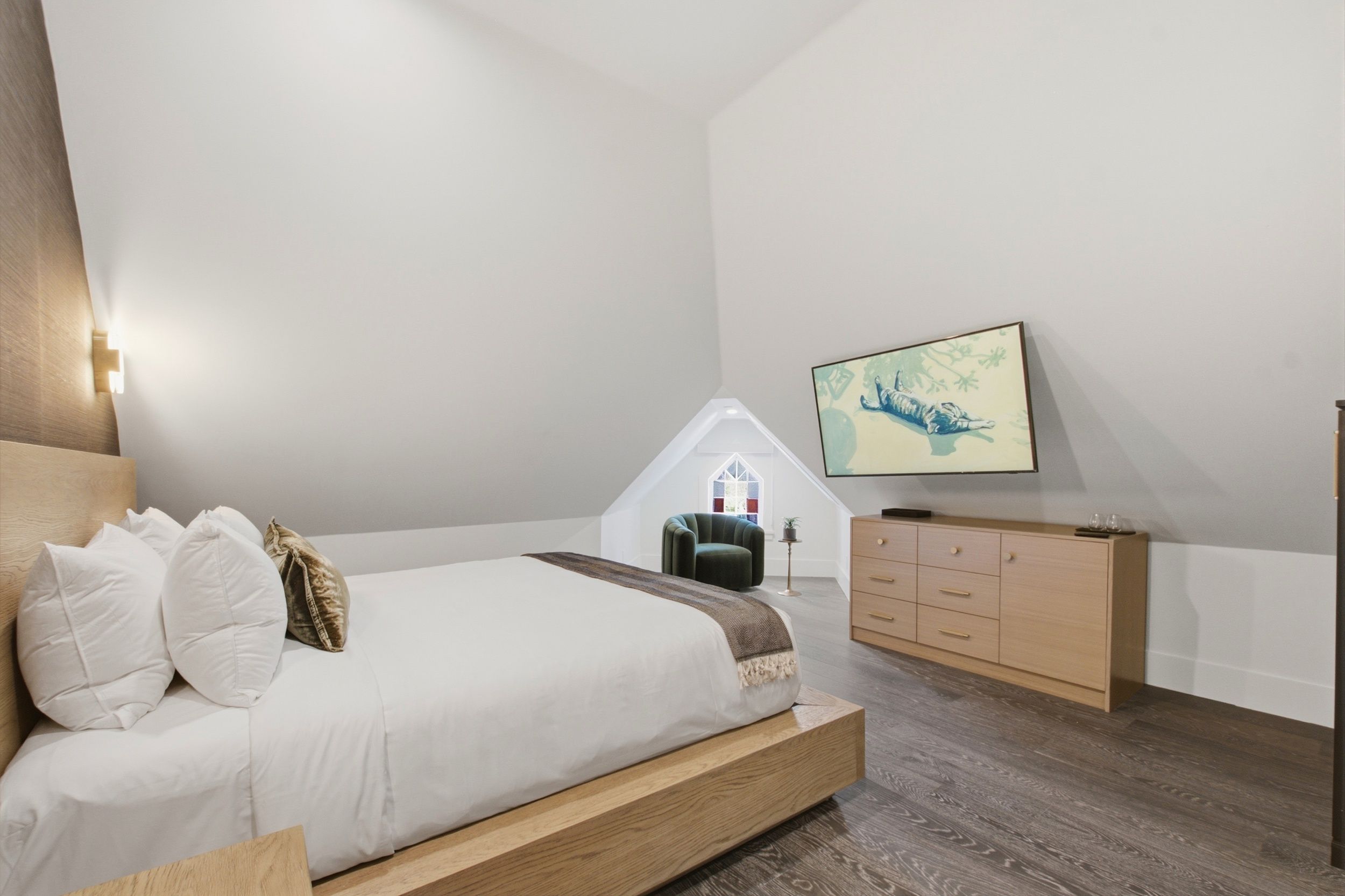 Une chambre à coucher avec un lit, une commode, une chaise et un tableau accroché au mur.