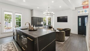 A modern kitchen with a large island, built-in appliances, and a chandelier.