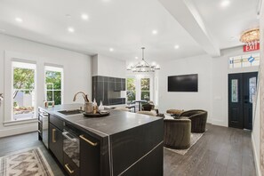 Una cocina moderna con una isla grande, electrodomésticos integrados y una lámpara de araña.