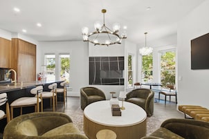 Una cocina moderna con barra, un comedor con mesa redonda y una sala de estar con sillones.