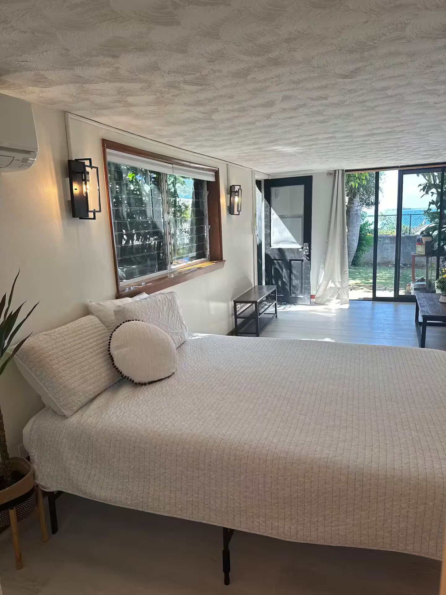 Une chambre dotée d’un grand lit, d’une fenêtre offrant une belle vue et d’une porte donnant sur un espace extérieur.