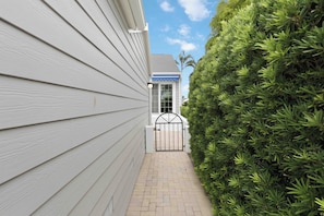 A narrow pathway leading to a gated entrance with a house in the background. - Come relax for a stay on Gorgeous Perico Bay Island. (Bradenton)