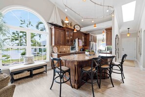 A spacious kitchen with a large island, dark wooden cabinets, and a view of a lake. - Come relax for a stay on Gorgeous Perico Bay Island. (Bradenton)