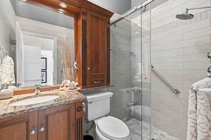 Ein Badezimmer mit einem Holzbadsatz, einer Duschkabine aus Glas und einer Toilette.