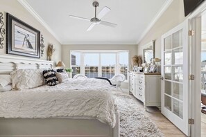 A bedroom with a large bed, a ceiling fan, a view of a lake through the windows, and a white wardrobe. - Come relax for a stay on Gorgeous Perico Bay Island. (Bradenton)