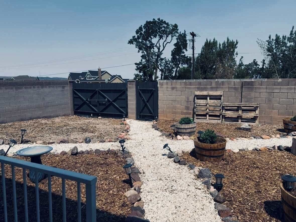 Un jardin avec un chemin de gravier, des plantes en pot et un banc en bois.