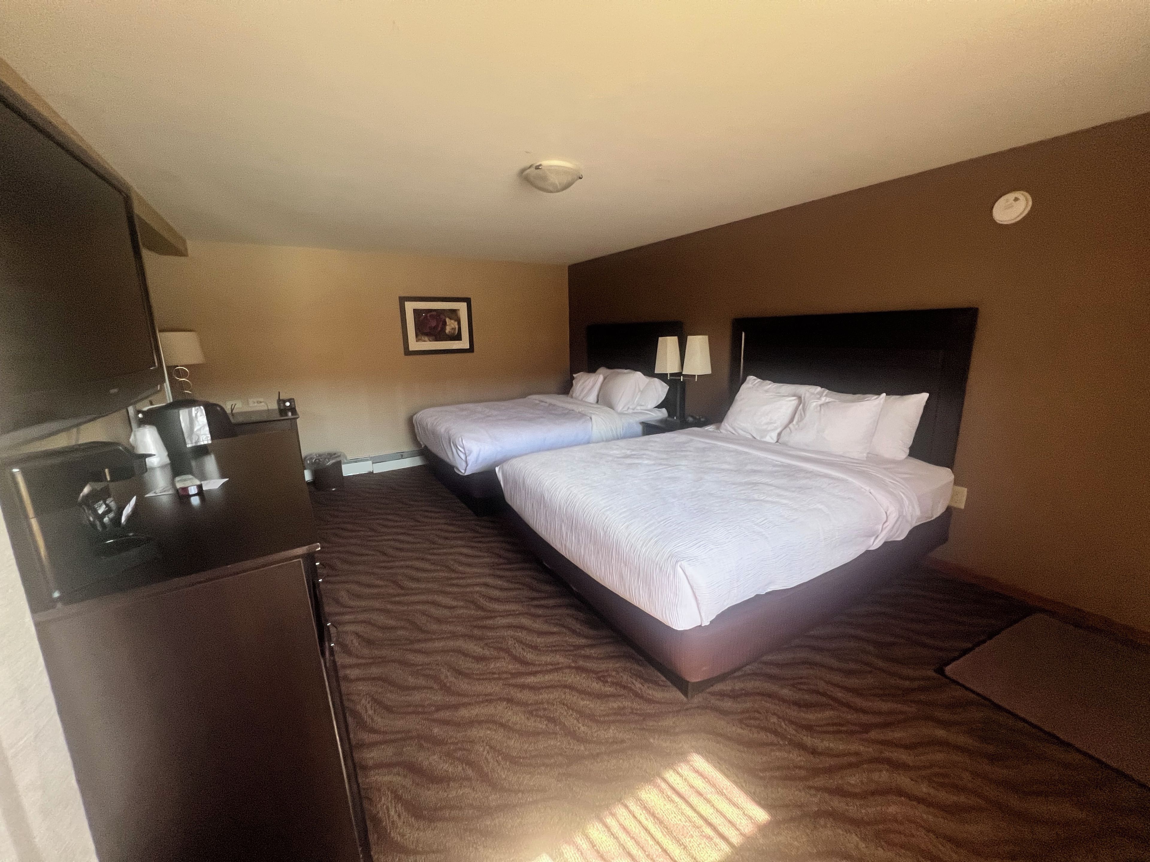 Une chambre d’hôtel avec deux lits, un bureau et une chaise.