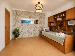 Ein Schlafzimmer mit einem Bett, einem Holzschrank, einem Spiegel und einer Zimmerpflanze.