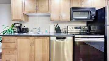 A kitchen with wooden cabinets, a stainless steel dishwasher, a microwave, an oven, and a sink.