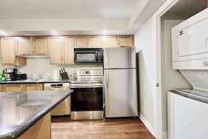 Una cocina moderna con armarios de madera, electrodomésticos de acero inoxidable y encimera de granito.