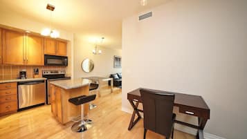 A modern kitchen with wooden cabinets, stainless steel appliances, a bar area, and a dining table with chairs.