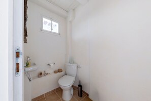 A small, white bathroom with a toilet, a sink, and a window. - Villa l'Écrin Beige - Les Portes en Ré (Les Portes-en-Ré)