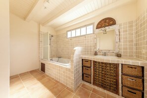 Un baño con bañera, ducha y tocador con espejo.