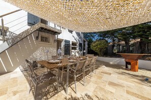 Un área de comedor al aire libre con una mesa dispuesta para cuatro personas, rodeada de sillas y cubierta por un dosel decorativo.