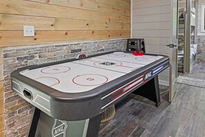 Ein Indoor-Shuffleboard-Tisch mit NHL-Branding, vor einer Holzwand mit Ziegeloptik und einer Tür zu einem Zimmer mit Bett und Schrank.