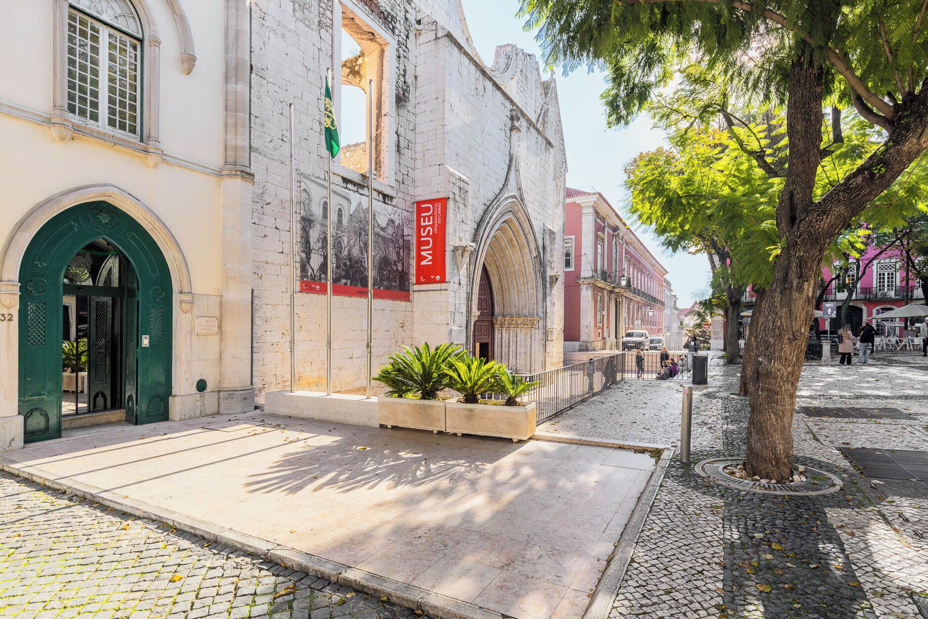A historic building with a green entrance, a red sign, and a cobblestone street.