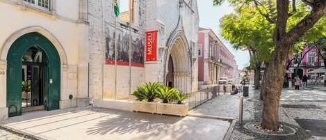 Um edifício histórico com entrada verde, placa vermelha e rua de calçada.