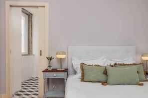 Un dormitorio con cama, lámparas de noche, mesita de noche y una puerta.