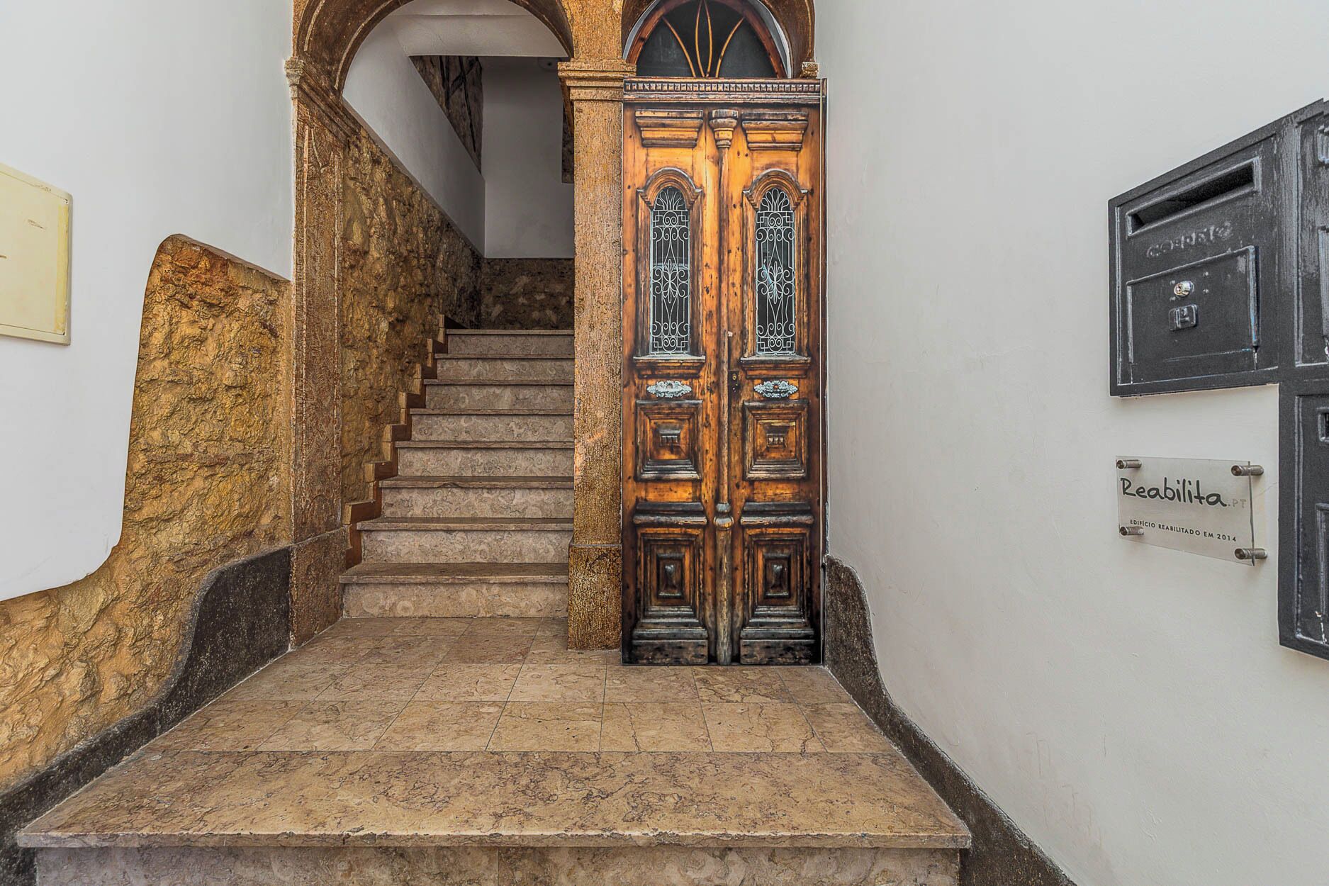 A staircase leading to a wooden door with a sign above it.