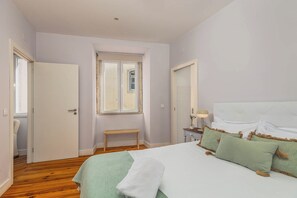 A bedroom with a bed, a nightstand, a lamp, a window, and a door. - Vintage-Chic Apartment in the City Center, Chiado (Lisboa)