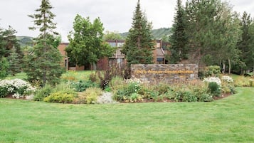 A building with a stone sign in front, surrounded by a well-maintained lawn and various trees.