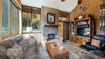 Un salon moderne avec une cheminée, un canapé en cuir, une table basse et une bibliothèque.