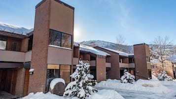 A multi-story building with a brick facade, large windows, and a snow-covered landscape in the background.
