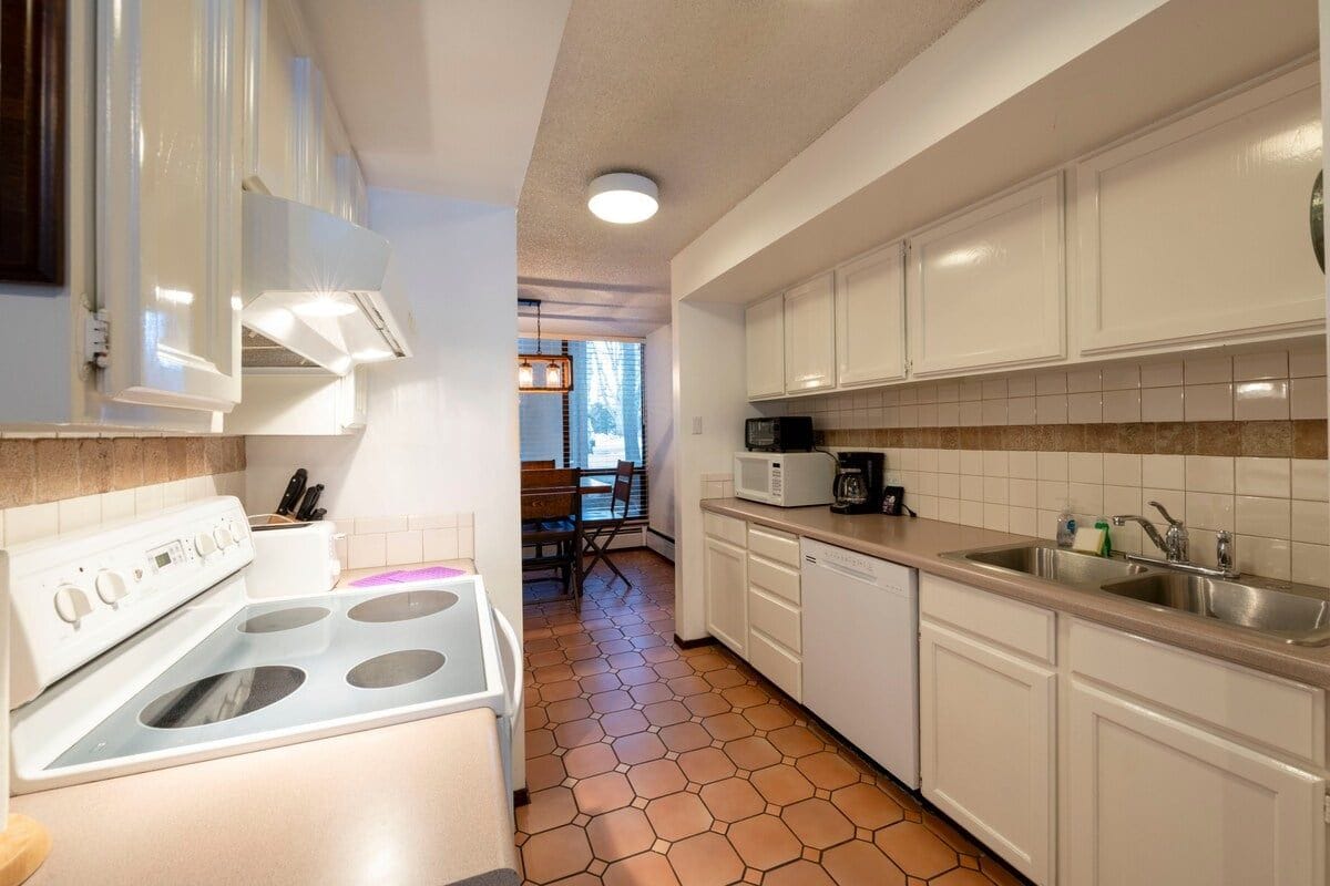 Una cocina con armarios blancos, estufa y microondas.