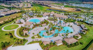 Luchtbeeld van een resort met meerdere zwembaden, een golfbaan en woongebouwen.