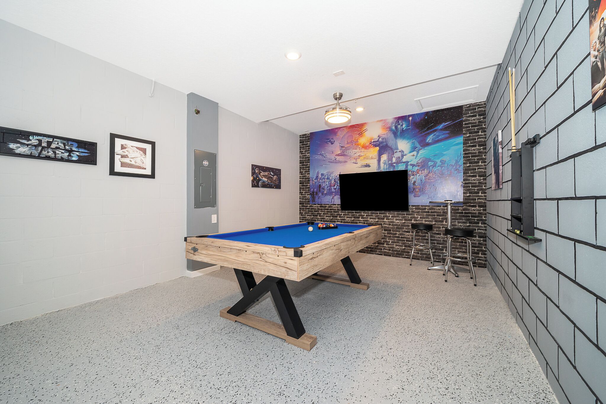 Une table de billard dans une pièce dont un mur est en briques et qui est ornée d’une grande fresque murale.