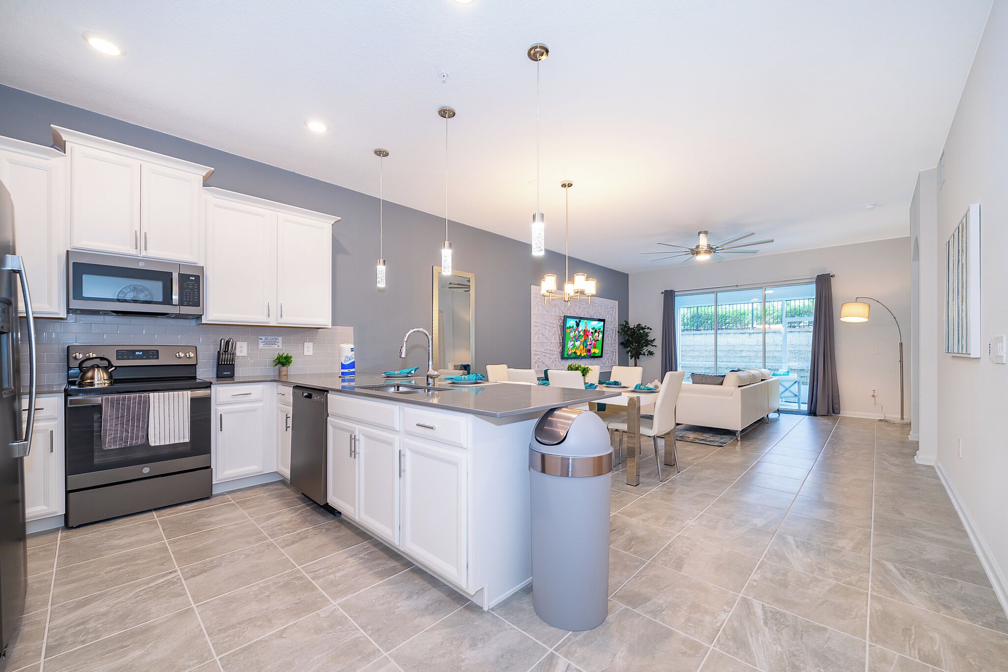 A modern kitchen with white cabinets, stainless steel appliances, and a large island.