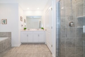 Een moderne badkamer met een douchecabine van glas, witte meubels en een grote spiegel boven de wastafel.