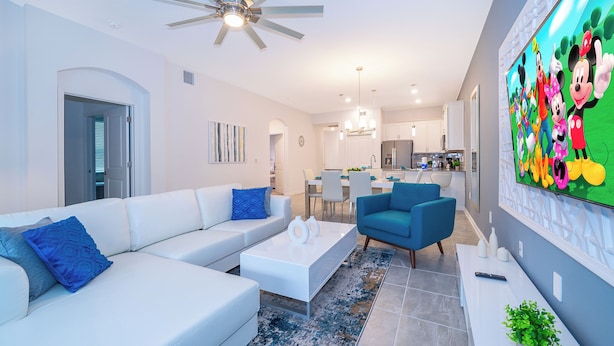 Un salon moderne avec un canapé blanc, un fauteuil bleu et un ventilateur de plafond.