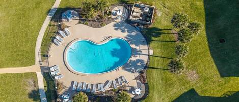 An aerial view of a swimming pool with lounge chairs and palm trees.