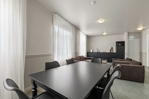 A conference room with a long table and chairs, a kitchenette area, and a door with an emergency exit sign. - Rare gem! 3BR/3BA Downtown Apartment in Reykjavik (Reykjavík)