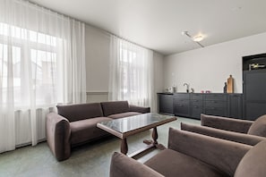 A modern living room with a sofa, a coffee table, and a kitchen area in the background. - Rare gem! 3BR/3BA Downtown Apartment in Reykjavik (Reykjavík)