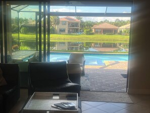 A room with a glass door leading to a pool area, a chair, and a table with a tray. - Charming house in Naples perfect for a relaxing getaway (Naples)