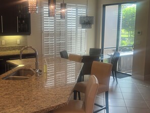 A kitchen with a granite countertop, stainless steel sink, and overhead pendant lights. - Charming house in Naples perfect for a relaxing getaway (Naples)