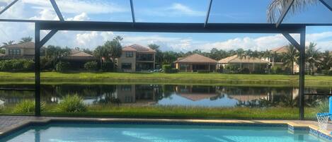 A pool area with a view of a residential complex and a pond.