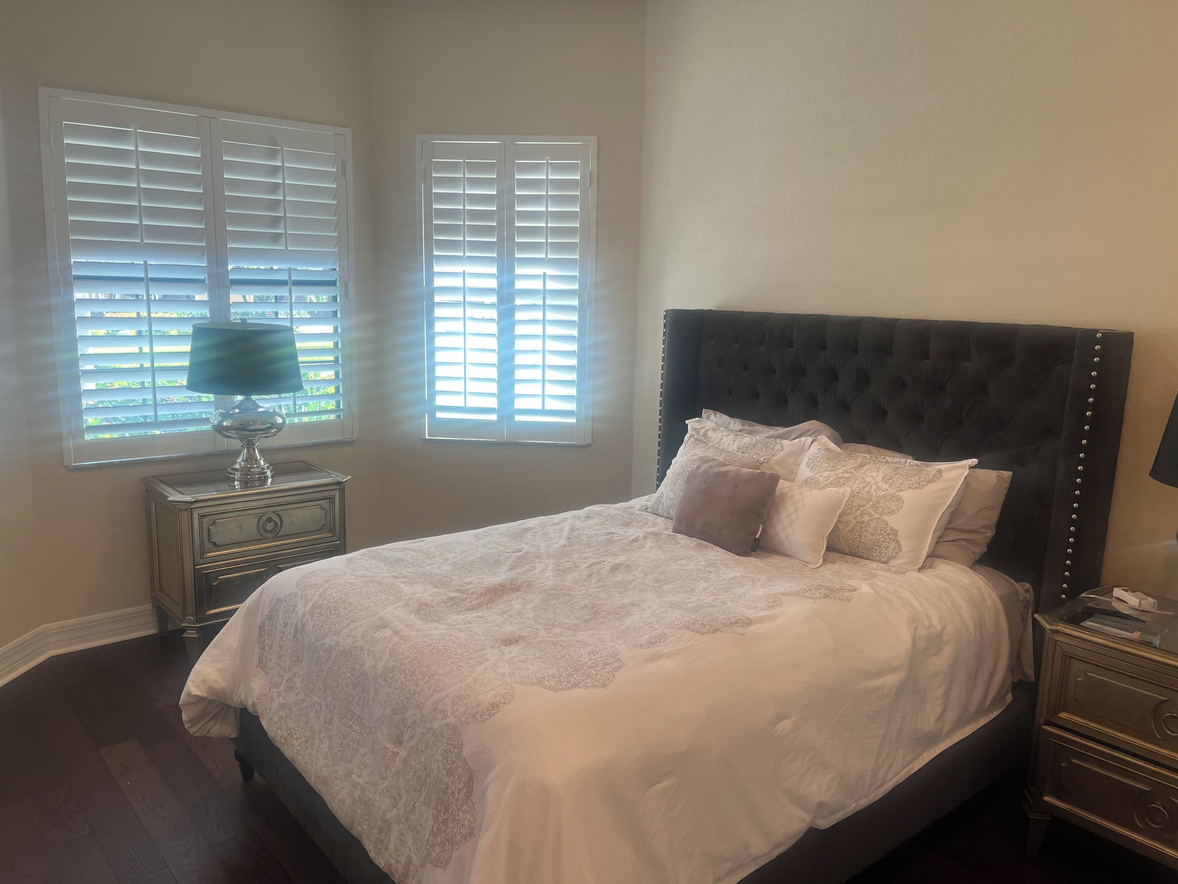 A bedroom with a large bed, two bedside tables, and a window with blinds.