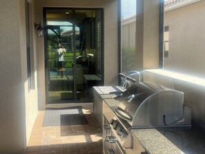 A patio with a grill, a door leading to a garden, and a wall-mounted light fixture. - Charming house in Naples perfect for a relaxing getaway (Naples)