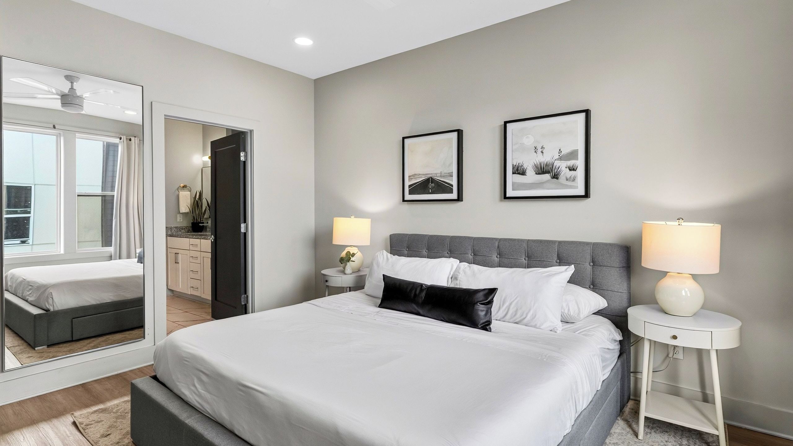 Ein modernes Hotelzimmer mit einem großen Bett, zwei Nachttischen, einem Spiegel und Bildern an der Wand.