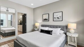 A modern hotel room with a large bed, two bedside tables, a mirror, and artwork on the wall. - Harmony House by Avantstay Sunlit Open Design + Island Kitchen Five Points + Broadway (Nashville)