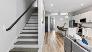 A modern kitchen with white cabinets, a stainless steel refrigerator, and a built-in oven. - Harmony House by Avantstay Sunlit Open Design + Island Kitchen Five Points + Broadway (Nashville)