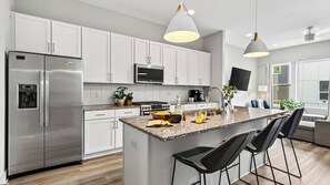 Eine moderne Küche mit Edelstahlgeräten, einer Granit Arbeitsplatte und Barhocker.