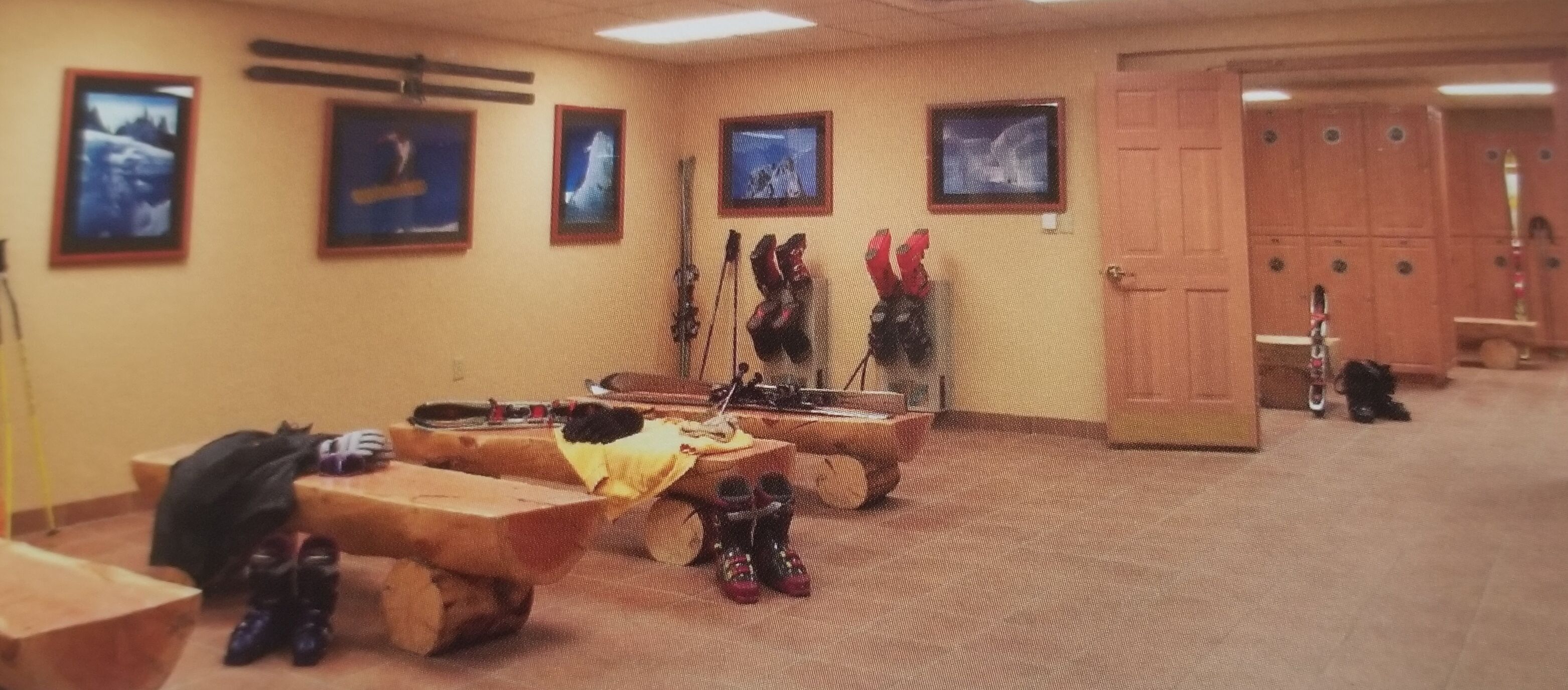 A room with a wooden bench, a coat rack with boots, and a door leading to a locker area.