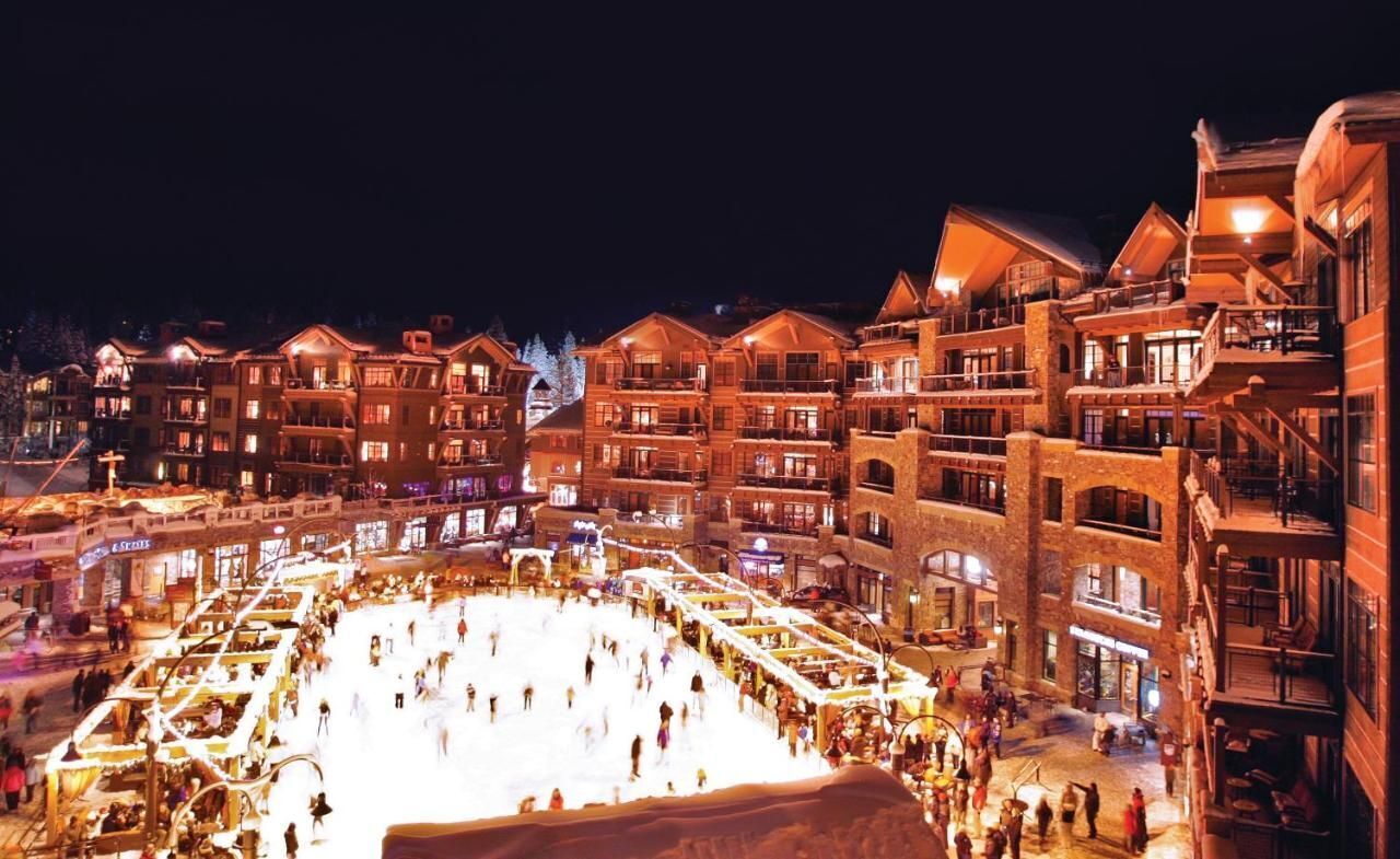 Un hotel de varios pisos con balcones, un patio central e una pista de hielo bien iluminada.