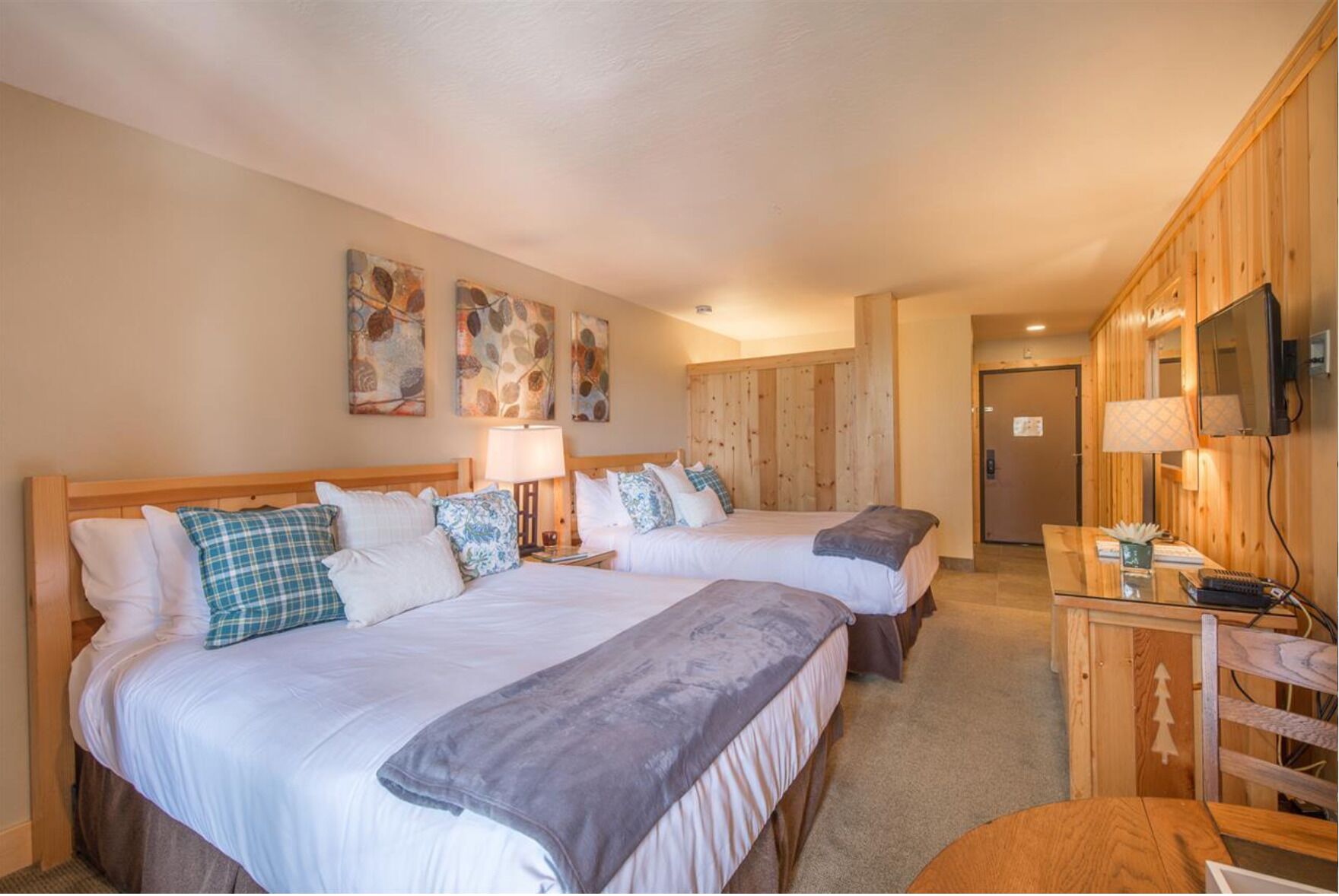 Bedroom with two beds, wood accents, and a wall-mounted television.