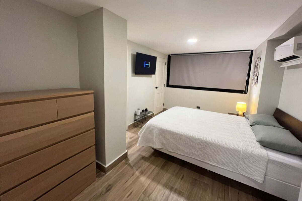Habitació d'hotel amb un llit, una televisió, una taula de treball i un armari.